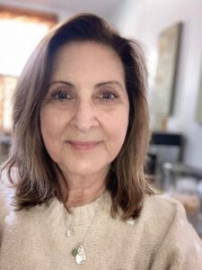 Wendy Sullivan A woman with shoulder-length brown hair and a beige sweater smiles softly at the camera in a bright room with blurred background details.